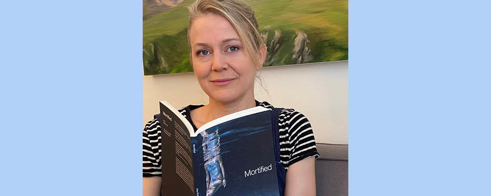 Amy Rutherford holding a copy of Mortified