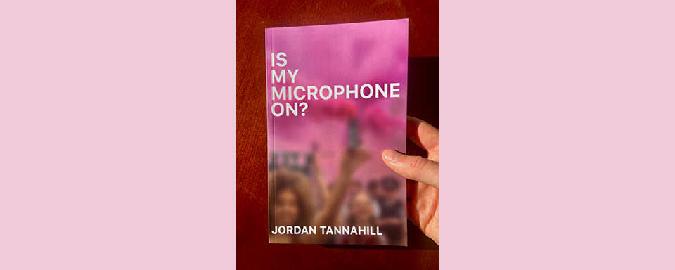 Jordan Tannahill holds a copy of Is My Microphone On?