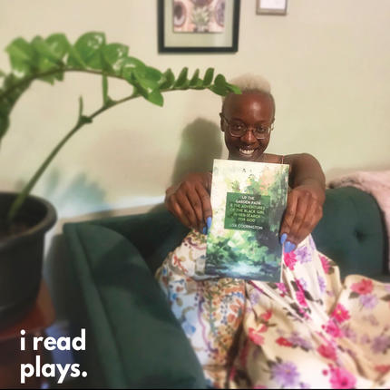 Natasha Mumba holds a copy of Up the Garden Path... up while sitting on a couch